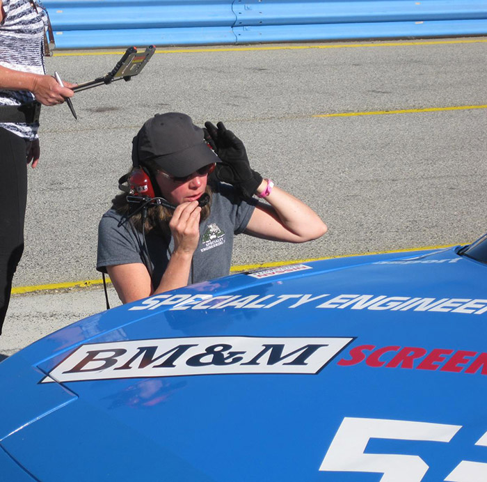 pit crew talking on headset while service blue race car with number 53